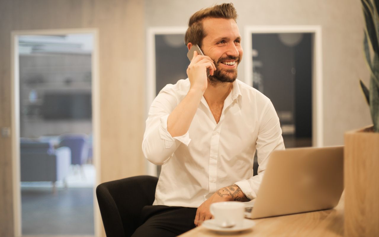 Team member logging working hours on a smartphone next to a laptop